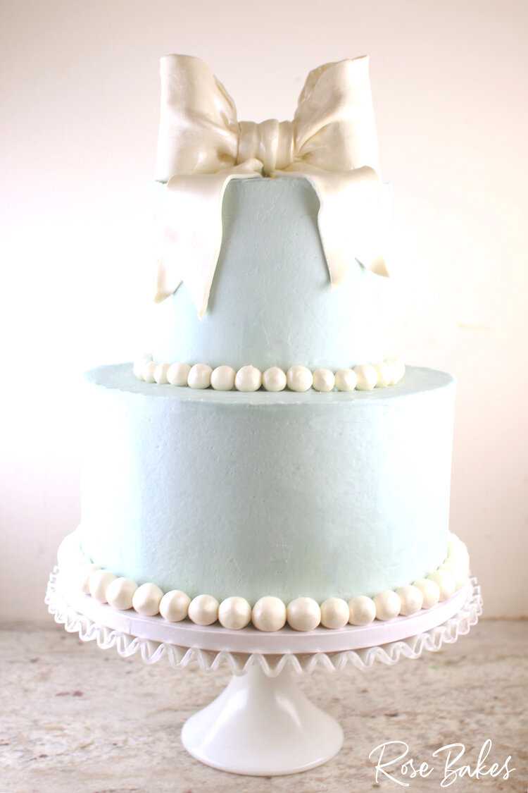 Baby Blue Baby Shower Cake - two tiers with pearl borders and a big white bow on top made from modeling chocolate.
