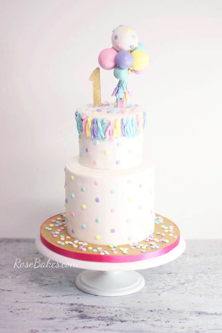 using melted candy melts for how to stick fondant decorations to cake on balloons and tassels cake