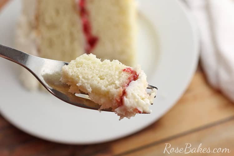 bite of white cake with raspberry filling and vanilla buttercream on a fork