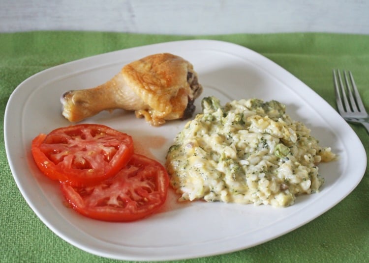 Easy Broccoli Rice & Cheese Casserole on white plate with tomatoe slices and baked chicken 