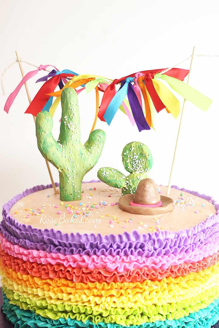 cactus cake topper with ribbon bunting on fiesta cake with rainbow buttercream ruffles