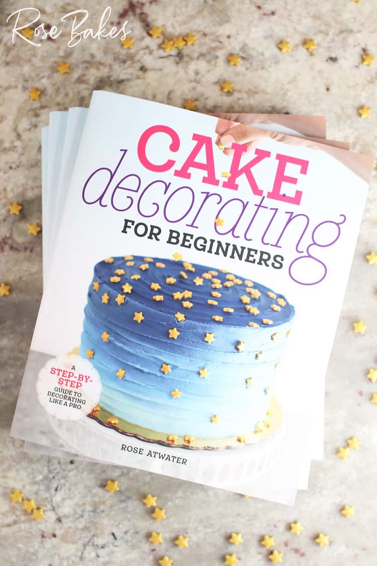 cake decorating for beginners book stacked on a counter with sprinkles