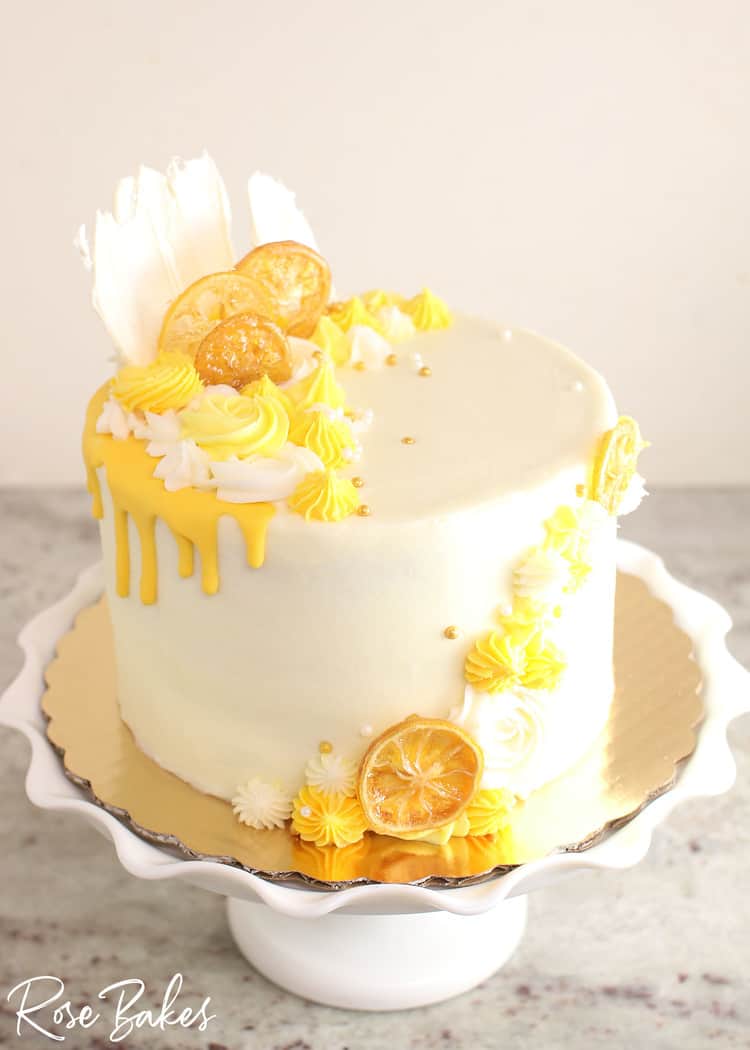 Lemon cake with vanilla buttercream, yellow drip, candied lemons and sprinkels and white chocolate