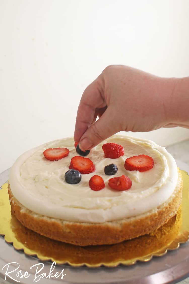 adding fresh fruit inside a layer of Berry Chantilly cake