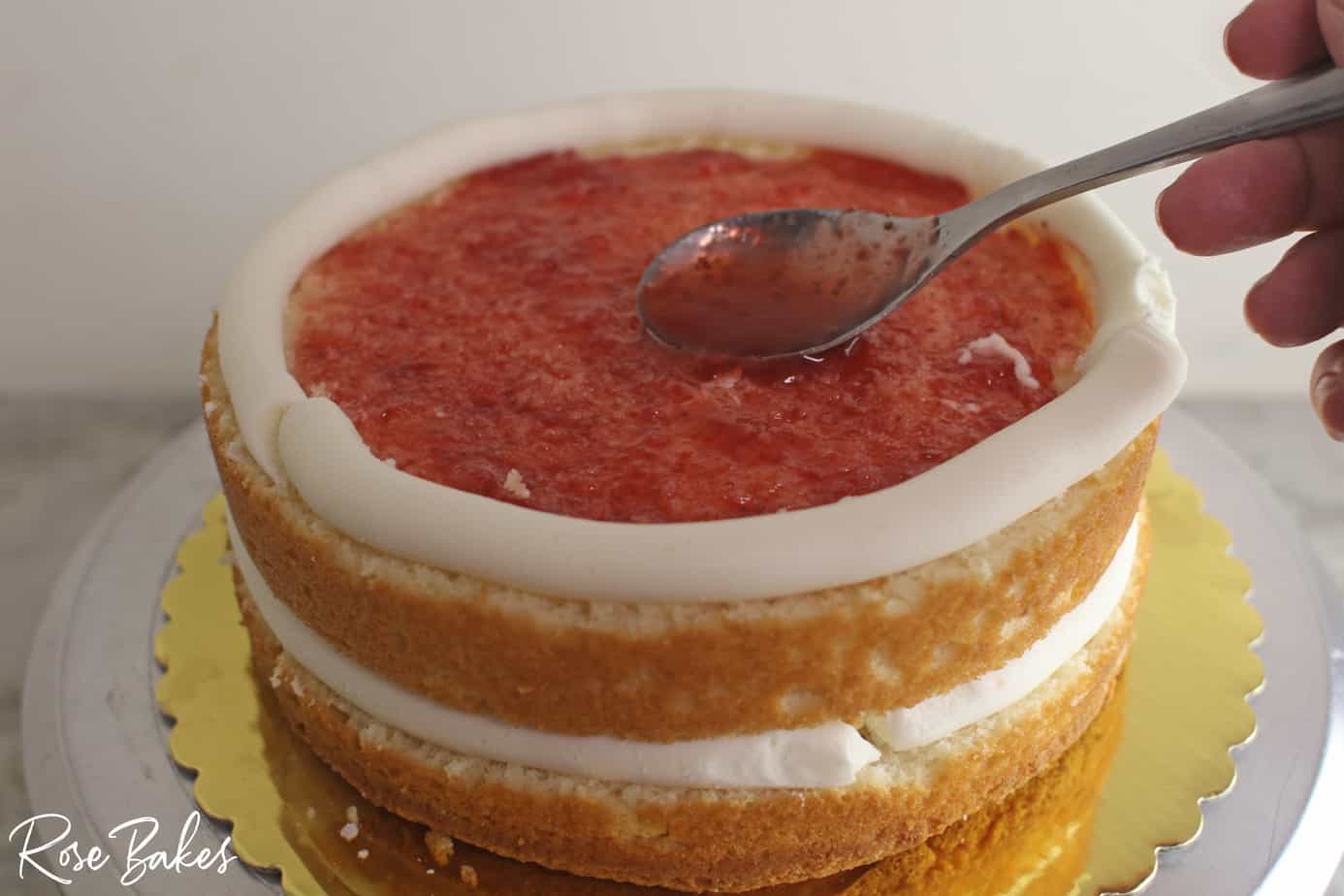 spreading fruit syrup on a cut layer of cake