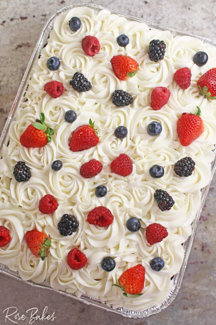 Chantilly Sheet Cake in a disposable pan. Cream Cheese frosting piped in rosettes and dotted with fresh berries on the top.
