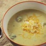 broccoli cheese soup in a white bowl on burlap placemat