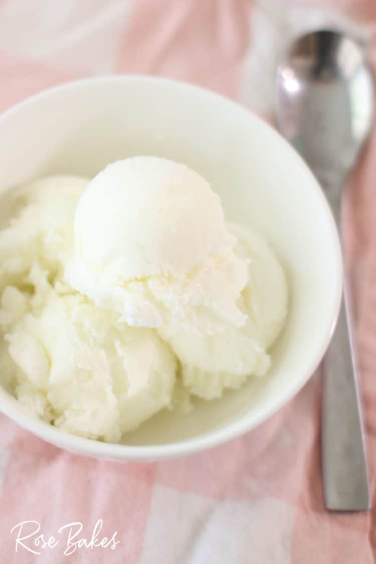 Easy Homemade Vanilla Ice Cream in a white bowl on pink cloth with spoon beside it
