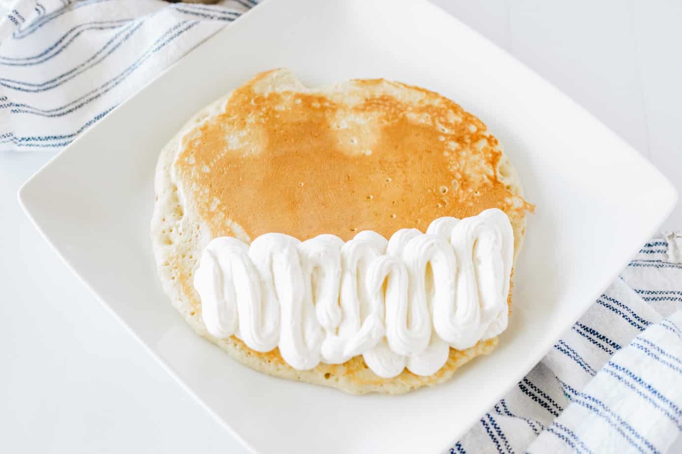 buttermilk pancake on a white plate with cheesecake mixture on half of it