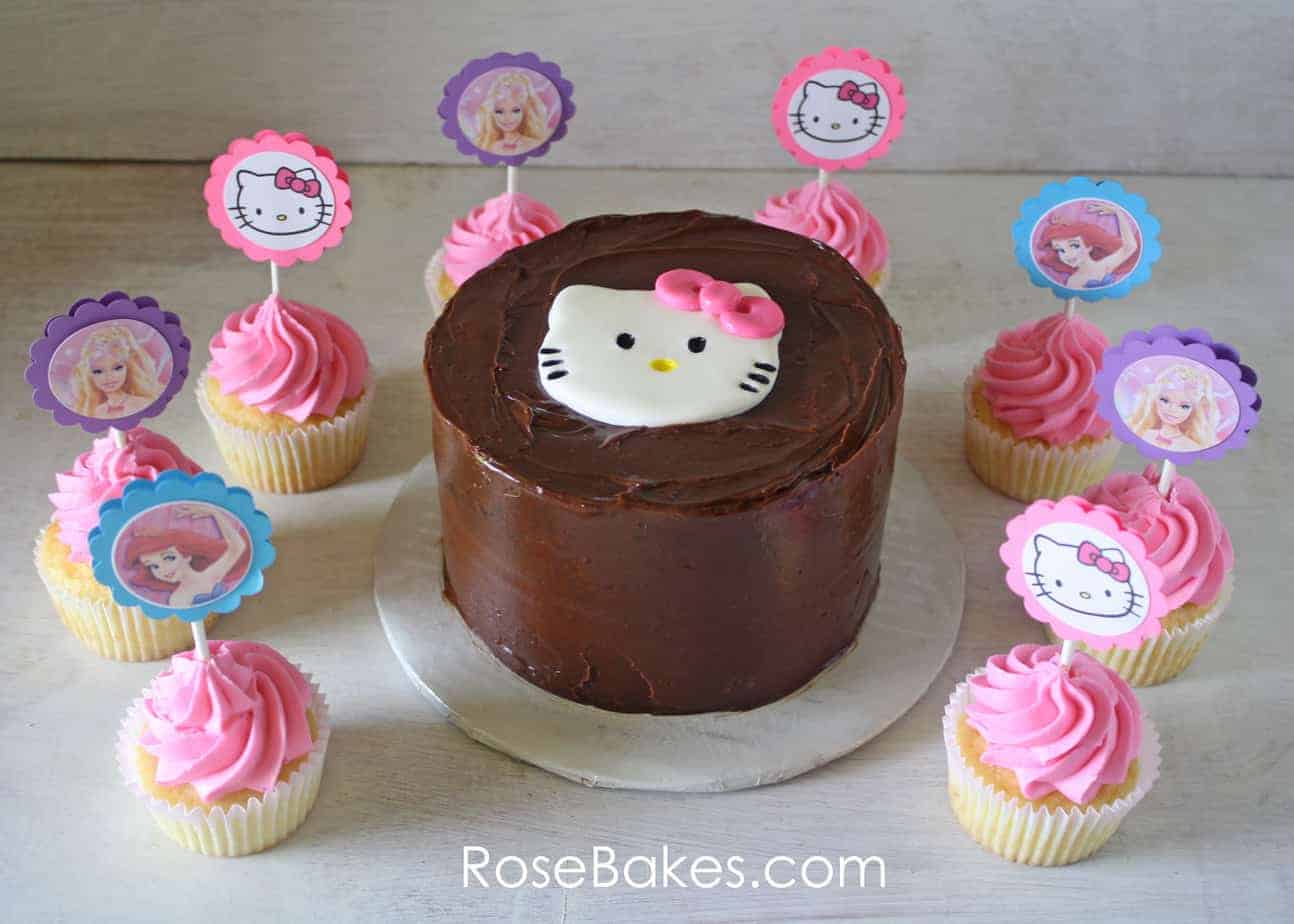 Chocolate Cake with a Hello Kitty Cupcake Topper surrounded by cupcakes with paper toppers
