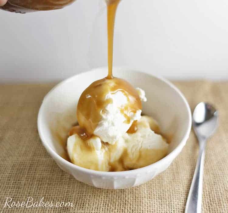 Homemade Caramel Sauce being poured over scoops of ice cream in a white bowl.