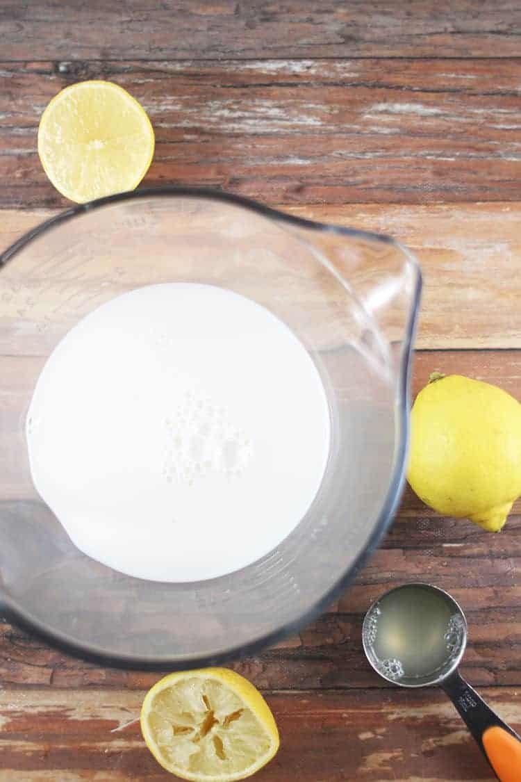 how to make buttermilk - cup of milk with sliced lemons and measuring spoon