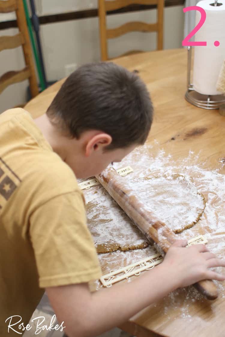 Kid rolling gingerbread dough on floured surface for How to Make Mini Gingerbread Houses with Kids post