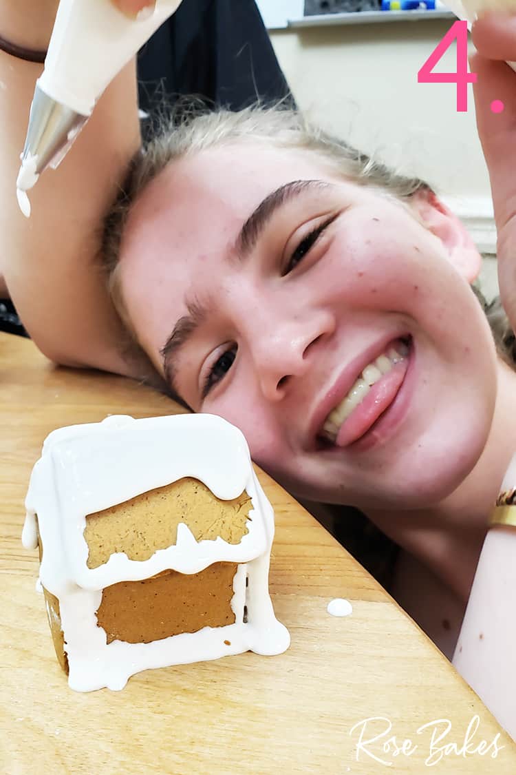 Girl with decorated mini gingerbread house and bag of icing