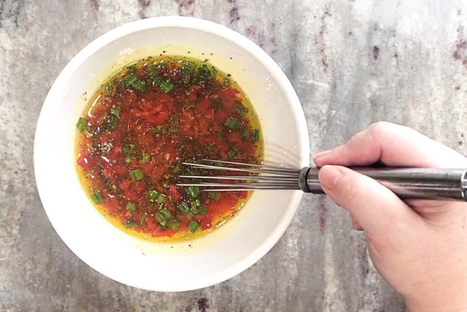 whisking spices into a bowl of pimentos, oil, green onions and vinegar