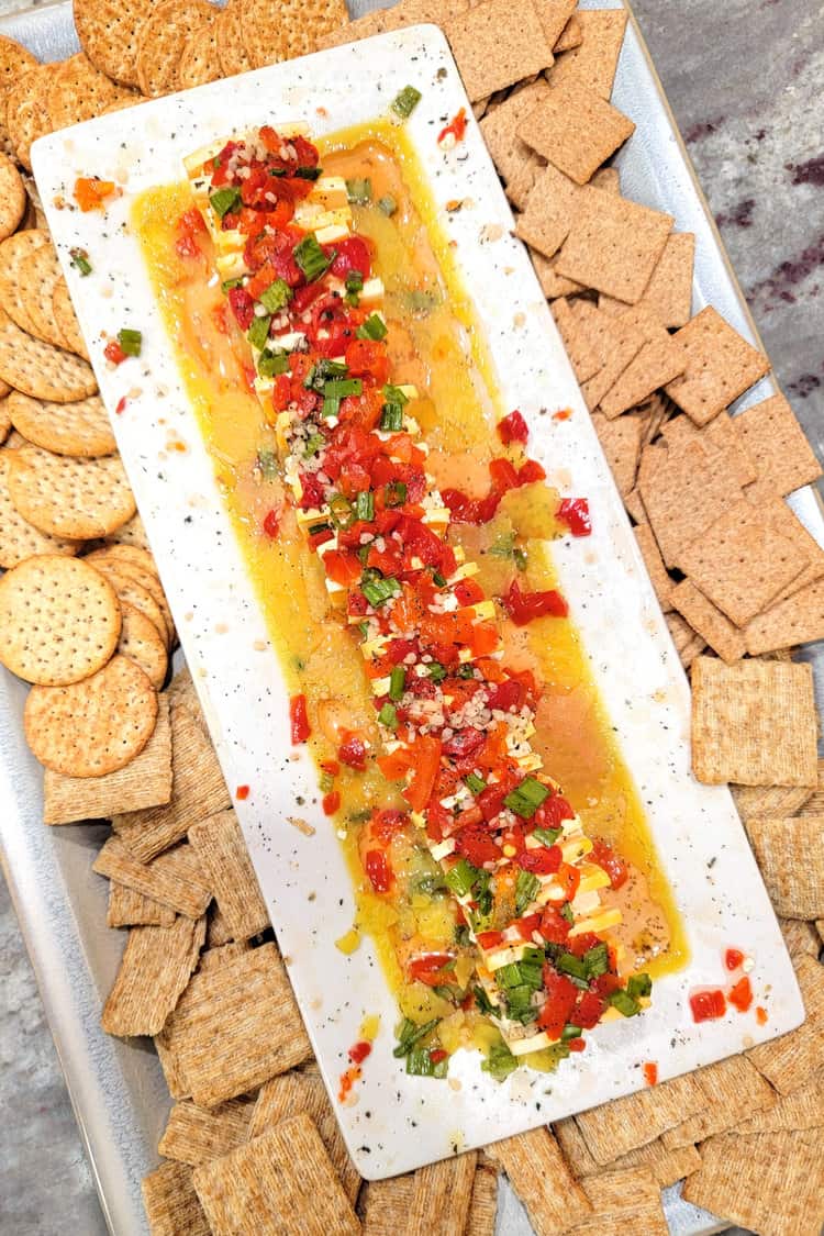 chilled marinated cheese on a platter surrounded by crackers