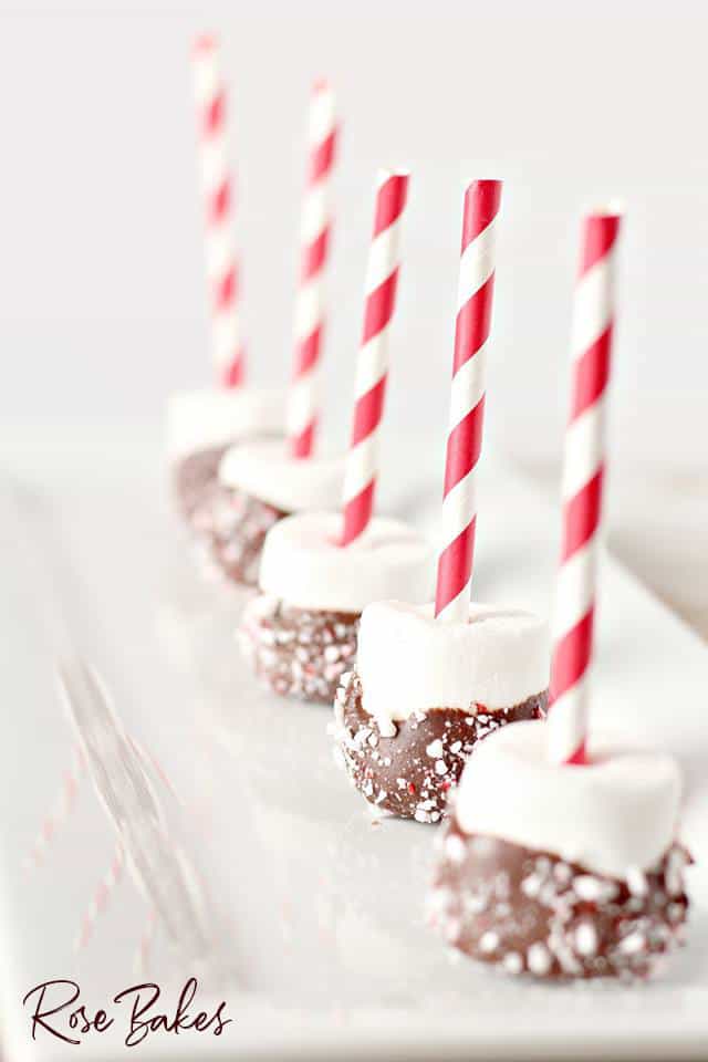 Peppermint Dipped Marshmallows for Hot Cocoa on red and white straws lined up on platter
