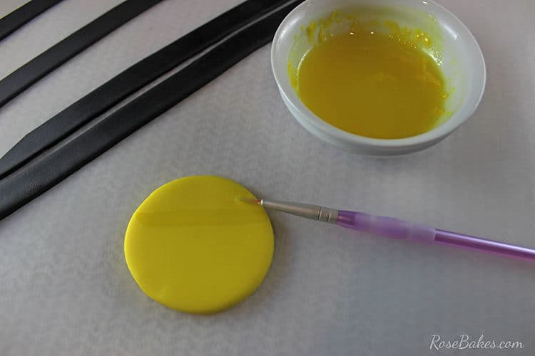 yellow fondant being painted with small paintbrush