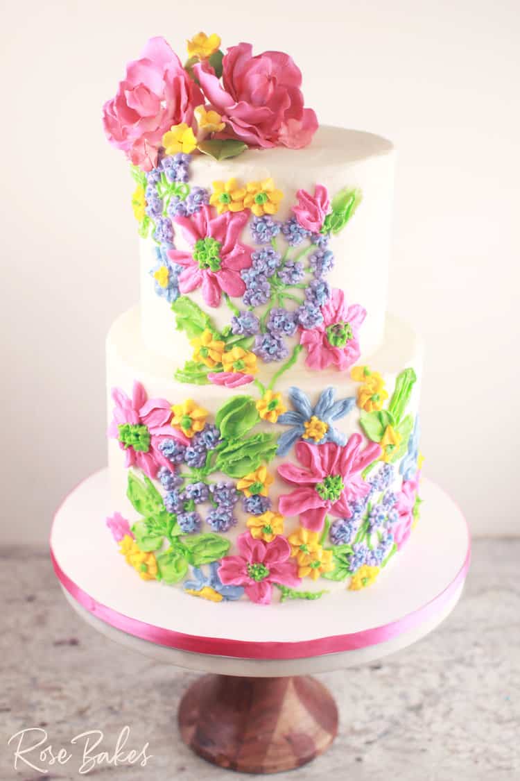 palette painted buttercream cake with multiple bright colors and sugar flowers on top
