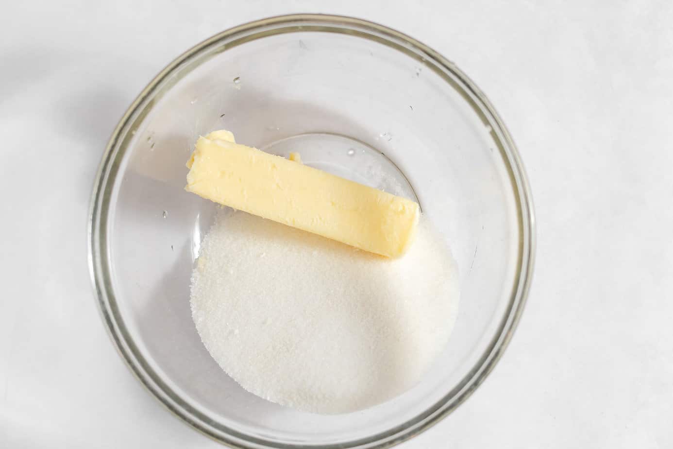 Butter and sugar added to a glass mixing bowl.