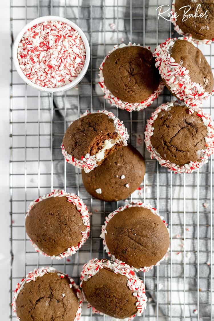 Chocolate whoopie pies with crushed peppermints around the centers on a wire rack.
