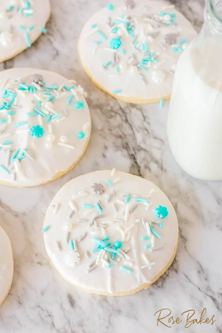 Sugar cookies with light blue, silver, and white sprinkles on a white counter
