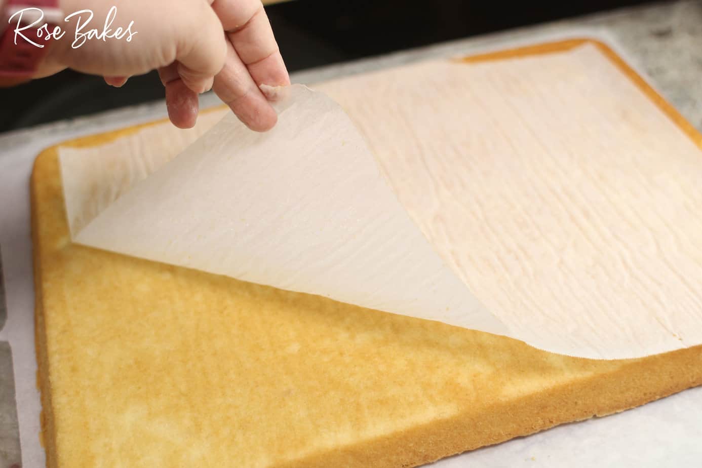 parchment paper being peeled off the baked cake.