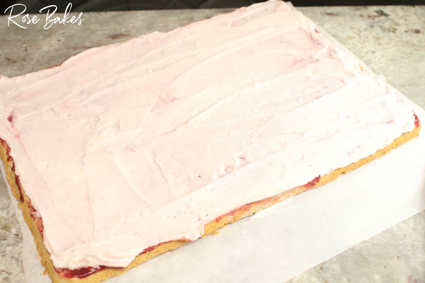 cake layer covered in raspberry filling and frosting.