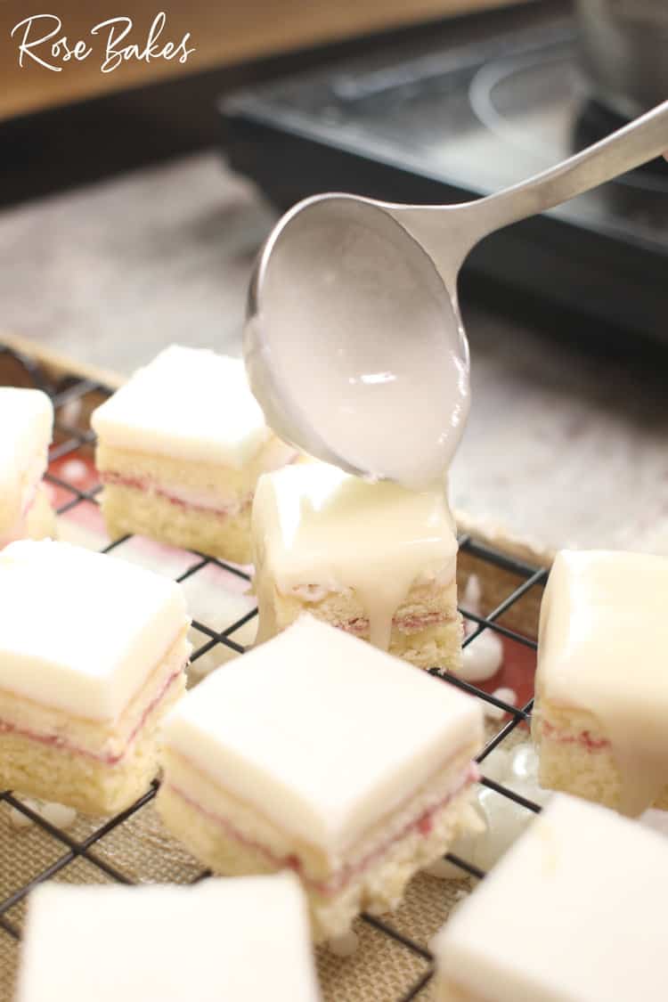 Petit four icing being ladled onto the squares of cake.