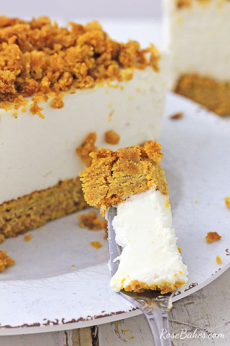 a bite of pumpkin bread bottom cheesecake on a fork leaning on a white plate
