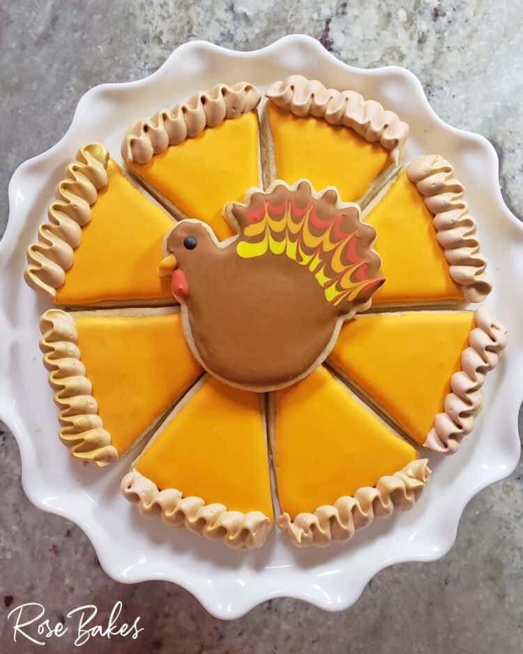 Slices of pumpkin pie cookies arranged like a whole pie with a decorated turkey cookie placed on top in the center 