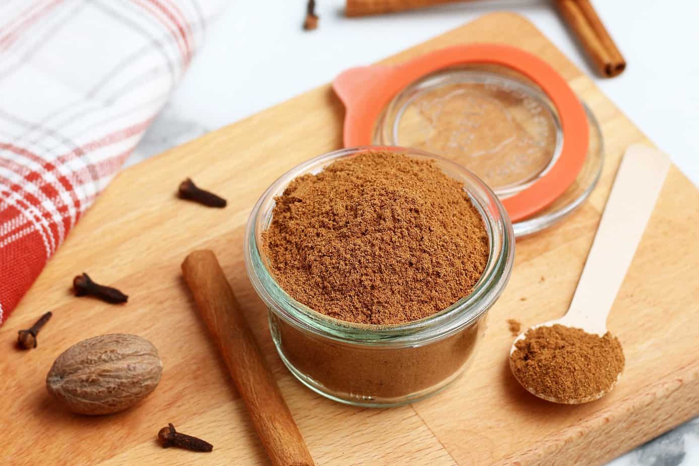 pumpkin pie spice ingredients in a small clear bowl on a cutting board