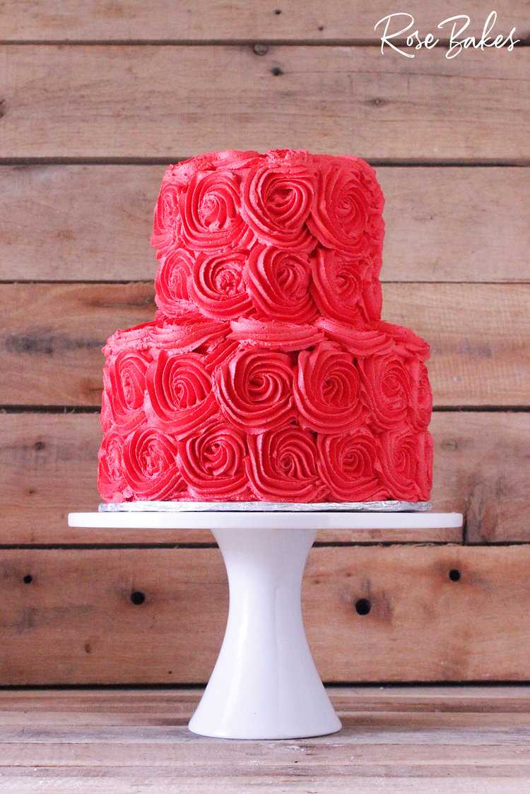 bright red buttercream cake with piped rosettes on a white cake stand
