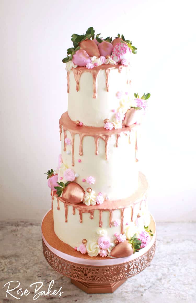 three tired rose gold drip cake with fresh strawberries and pink piping