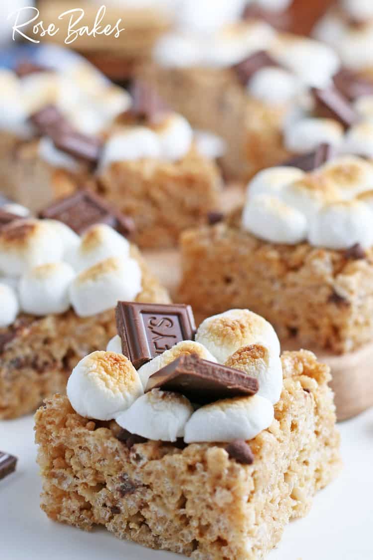 close up of a smore rice krispie treats cut into squares and sitting on a wooden cutting board and white counter