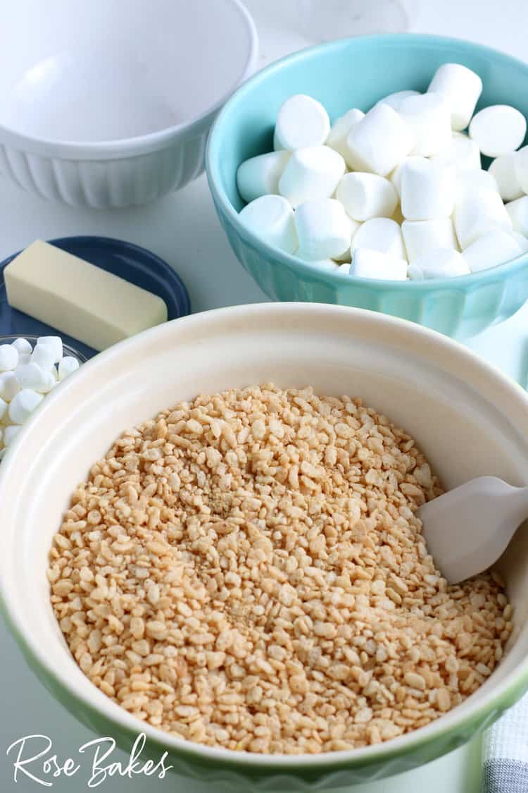 rice cereal in a green bowl with a bowl of marshmallows and stick of butter in the background