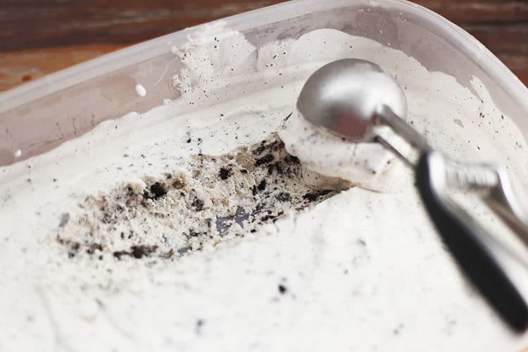 Homemade OREO Cookies and Cream Ice Cream being scooped from plastic freezer bowl