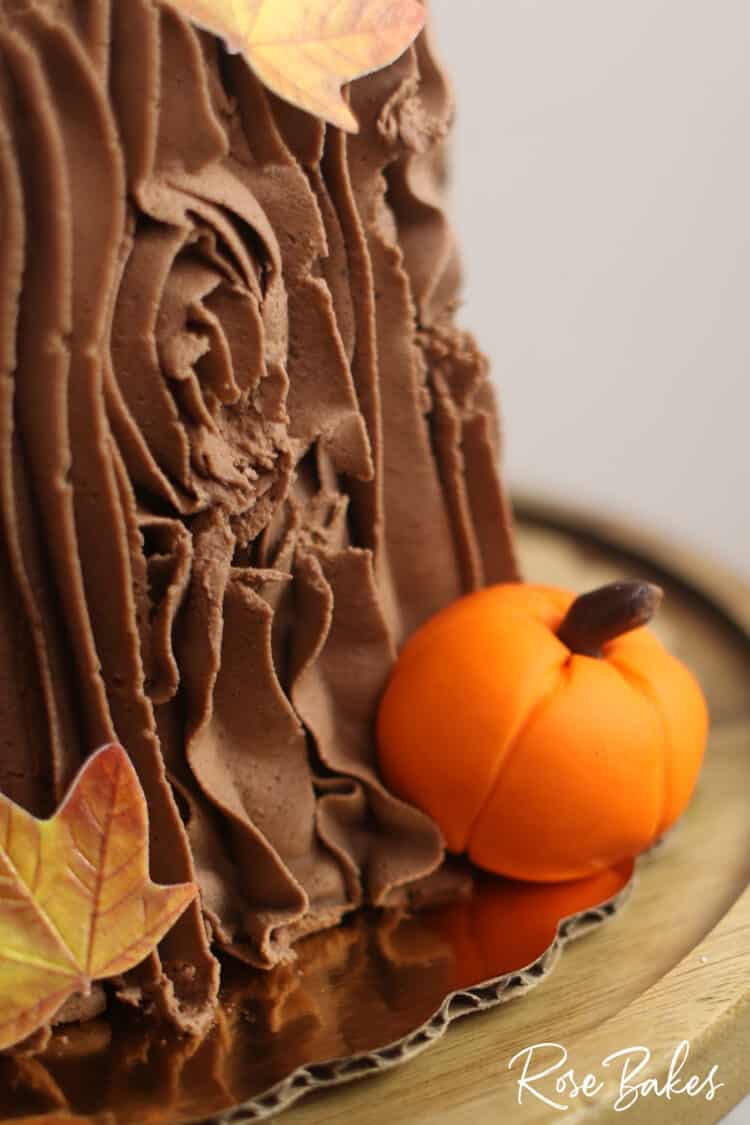 Easy Fall Tree Stump Cake closeup of chocolate buttercream, edible leaf and fondant pumpkin