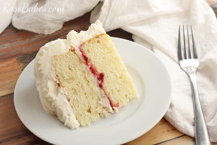 white cake with raspberry filling and vanilla buttercream on a white plate