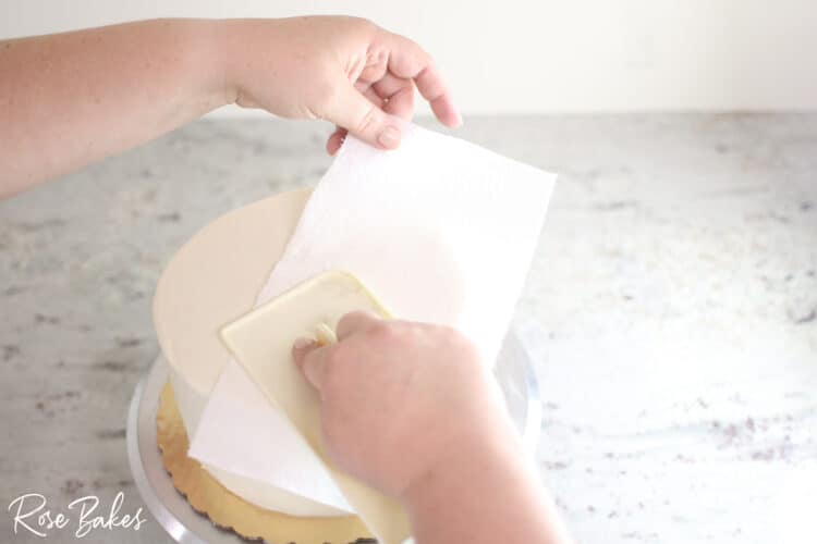 viva towel smoothing top of buttercream icing cake to create smooth seamless look