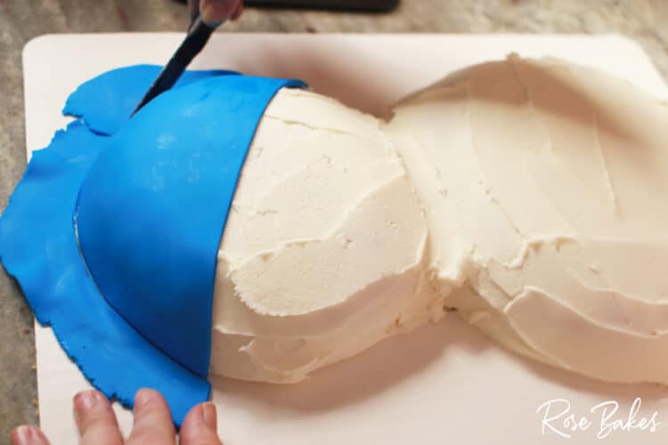 blue fondant being placed on cake 