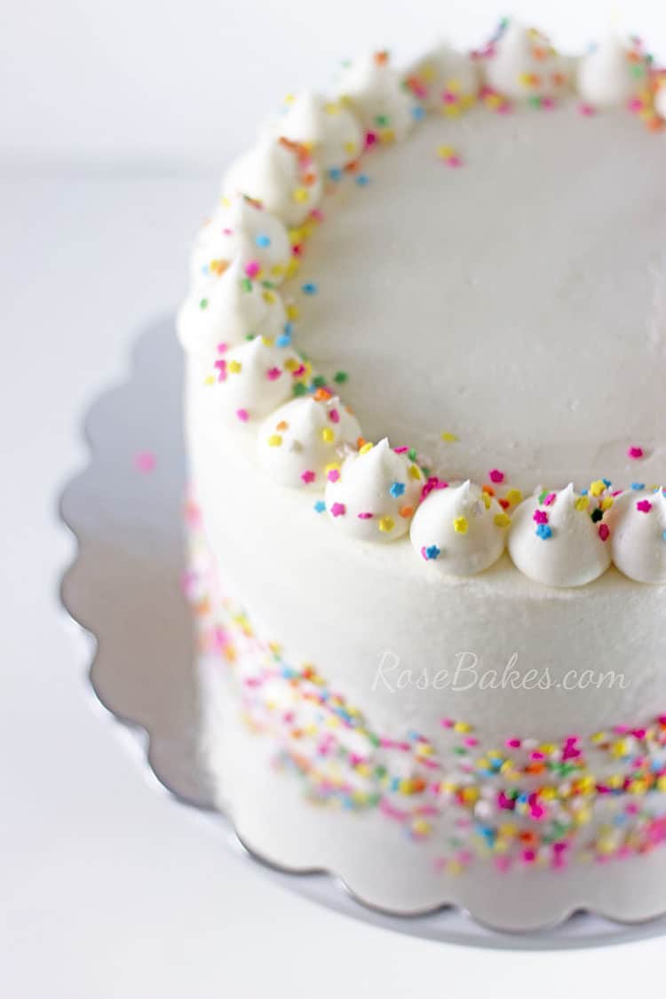 small cake covered in white vanilla buttercream and rainbow sprinkles