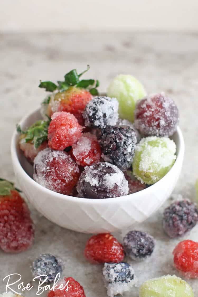 White bowl filled with sugared berries and grapes.