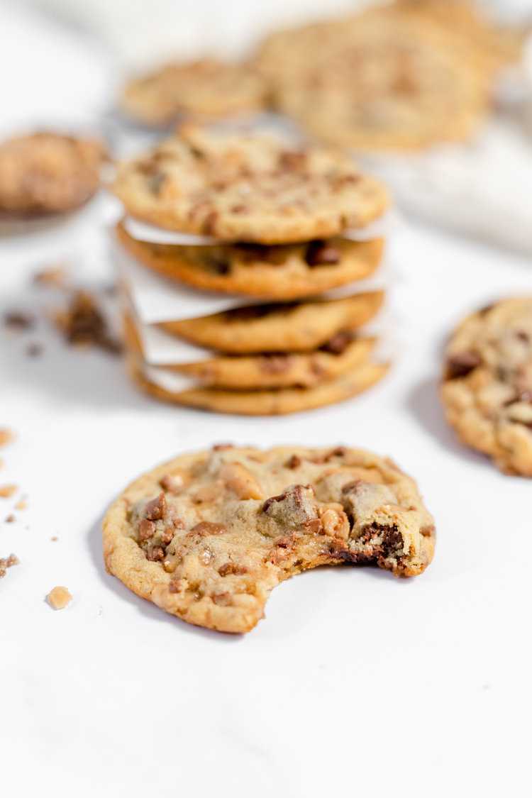 stack of toffee chocolate chip cookies on a plate - one cookie has bite missing