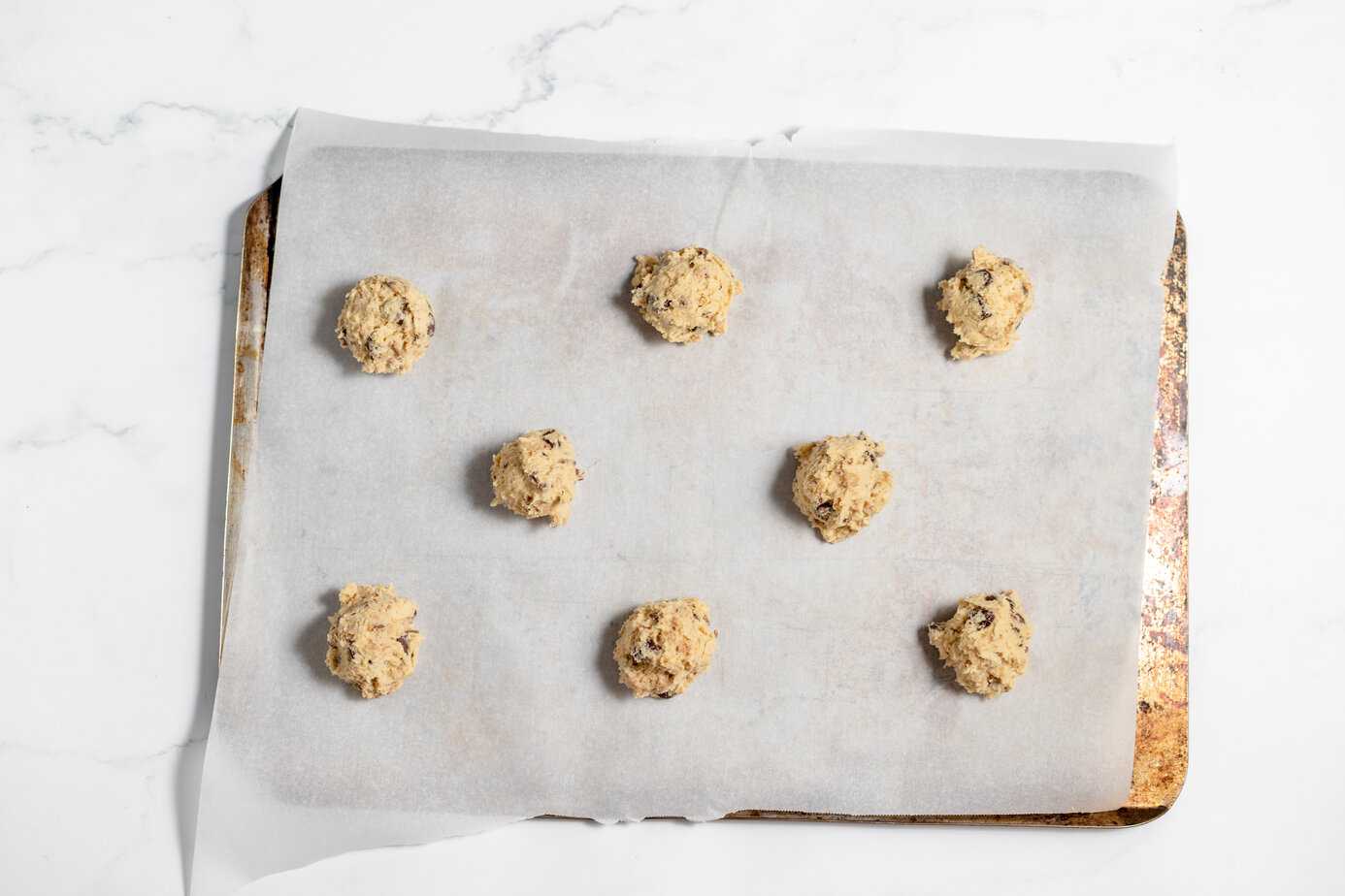 balls of cookie dough on a cookie sheet with parchment