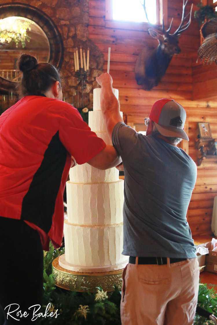man and woman stacking tiers of a wedding cake