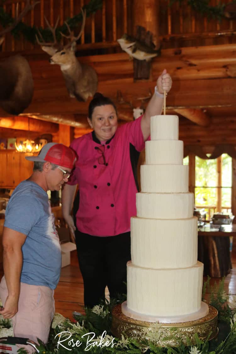 woman holding a dowel in the top of a wedding cake
