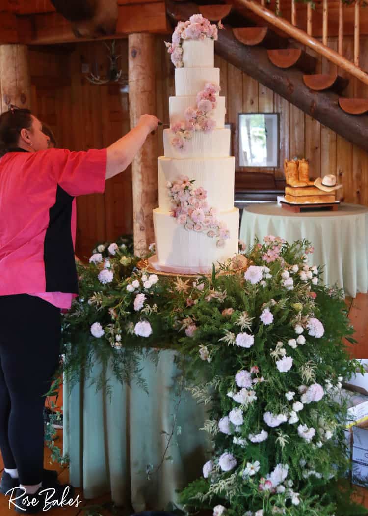 Rose adding flowers to a tall vertical lines in buttercream wedding cake