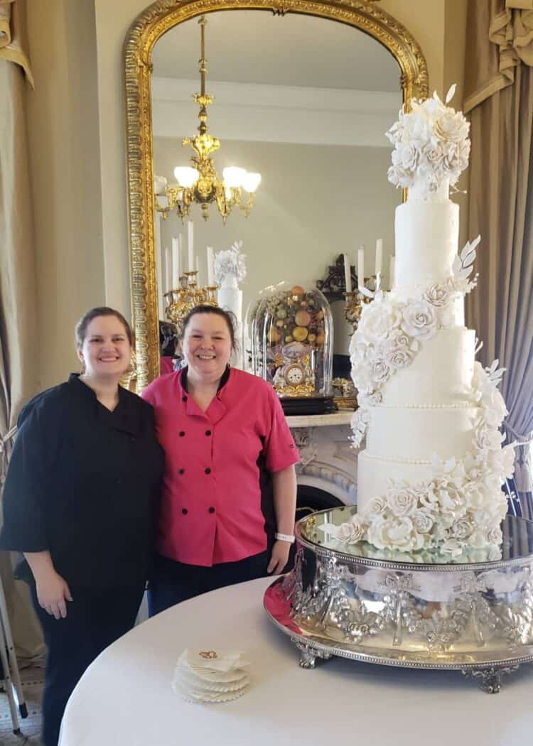 9 tier tall elegant luxury wedding cake with sugar flowers and Rose Atwater baker standing next to 