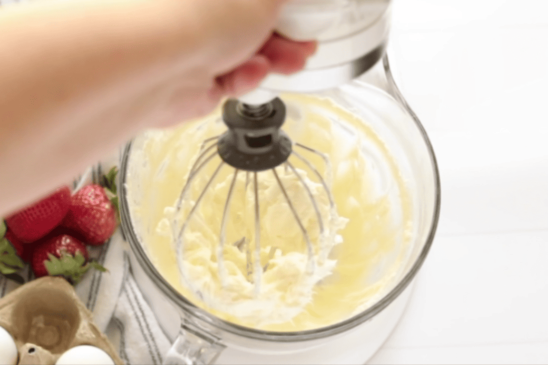 whipping cream cheese and powdered sugar in a glass mixing bowl